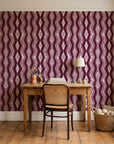 Gilded Rain Oxblood geometric wallpaper behind a vintage writing desk in a cozy craft-room home office