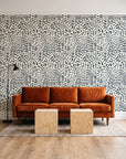 Grain Shift Oatmeal minimalist dash wallpaper behind a rust velvet sofa in a bright coworking lounge