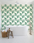 Harvest Crown Emerald leafy branch wallpaper behind a freestanding tub in a bright coastal bathroom