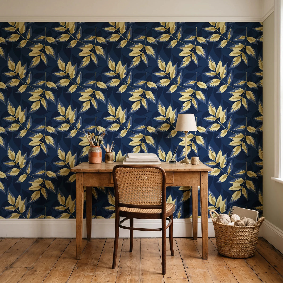 Harvest Crown Midnight leafy branch wallpaper behind a vintage writing desk in a cozy craft-room home office