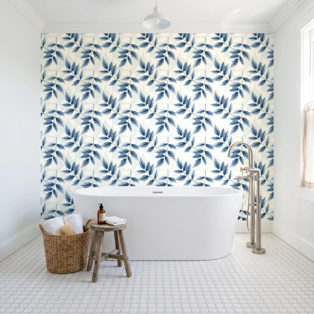 Harvest Crown Slate leafy branch wallpaper behind a freestanding tub in a bright coastal bathroom