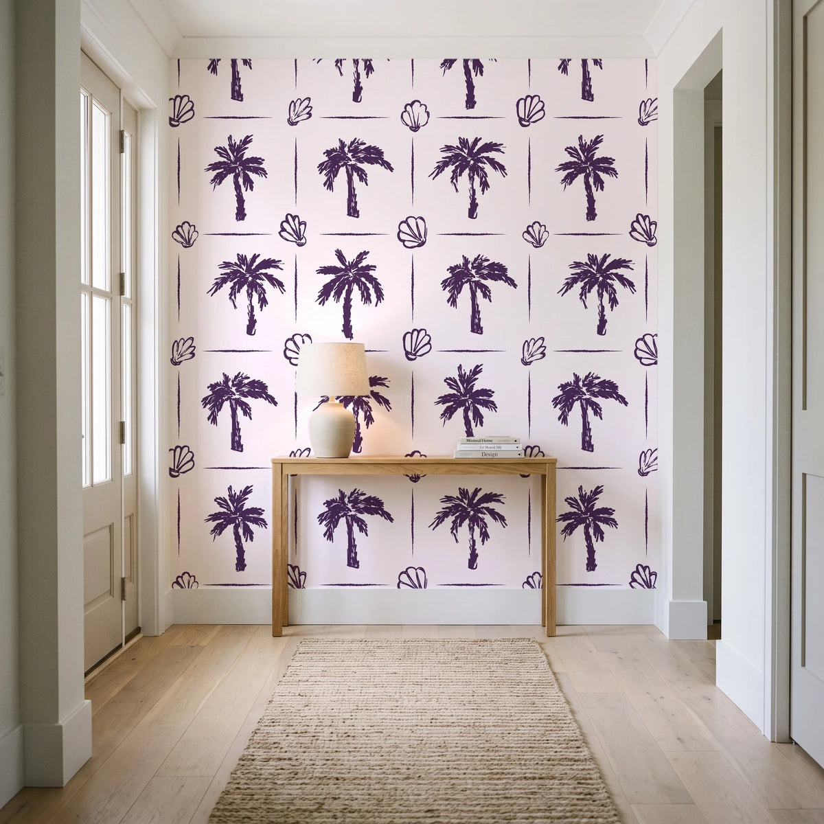 Ink & Shell Aubergine coastal palm and shell wallpaper behind a console table in a light entry hallway
