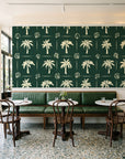 Ink & Shell Forest coastal palm and shell wallpaper above a green leather banquette in a sunlit neighborhood cafe