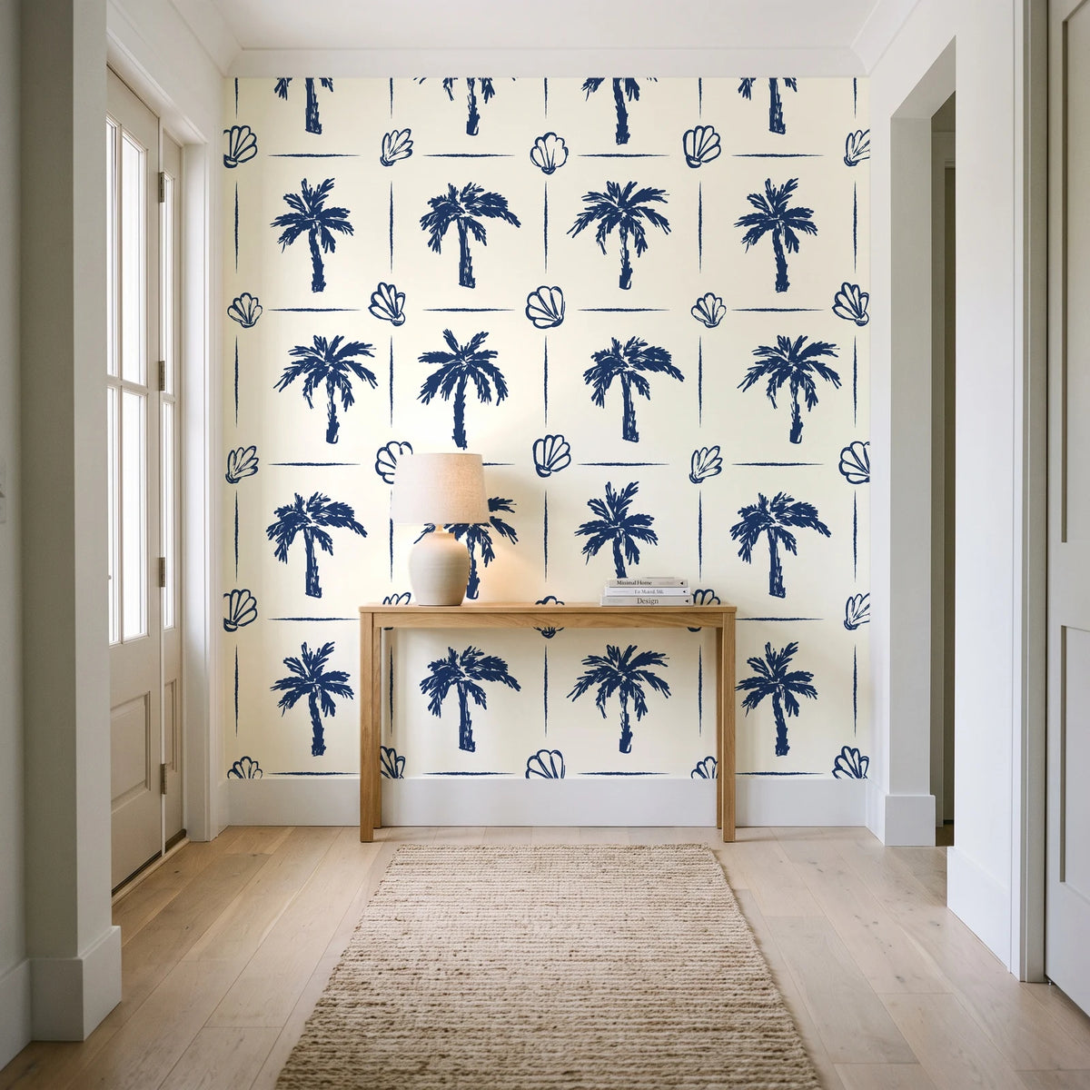 Ink & Shell Navy coastal palm and shell wallpaper behind a console table in a light entry hallway
