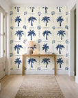 Ink & Shell Navy coastal palm and shell wallpaper behind a console table in a light entry hallway