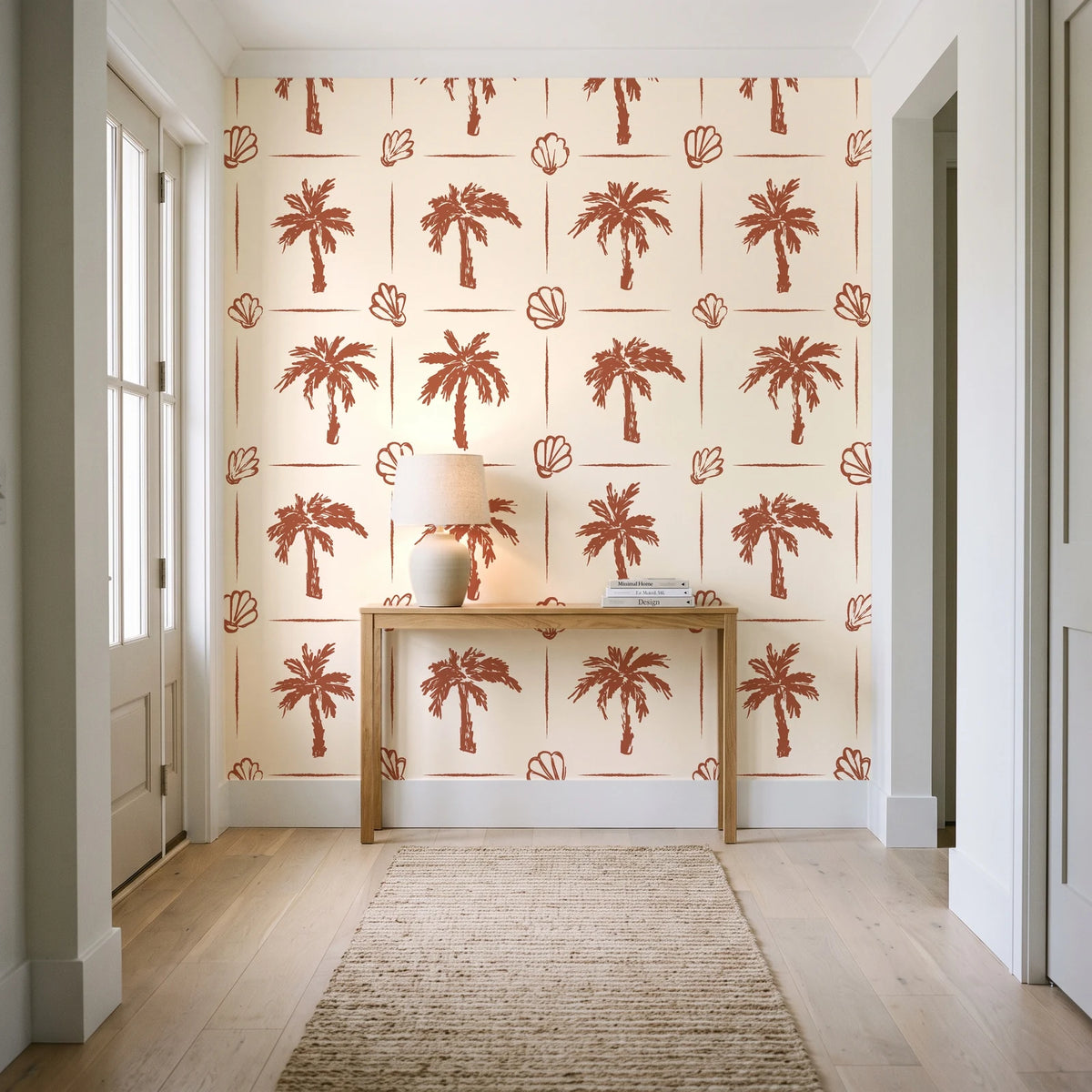Ink & Shell Terracotta coastal palm and shell wallpaper behind a console table in a light entry hallway