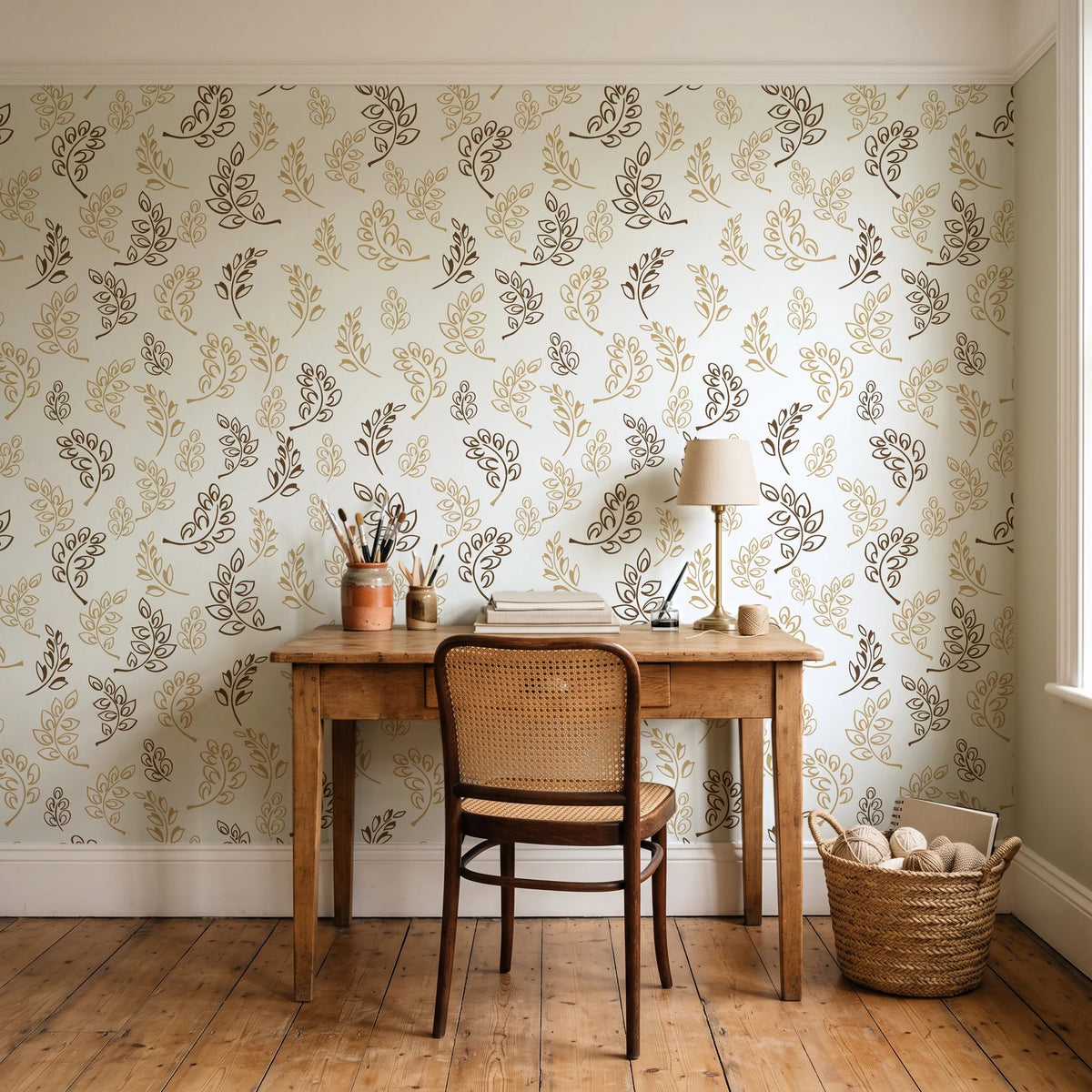 Ink & Sprig Bronze botanical sprig wallpaper behind a vintage writing desk in a cozy craft-room home office