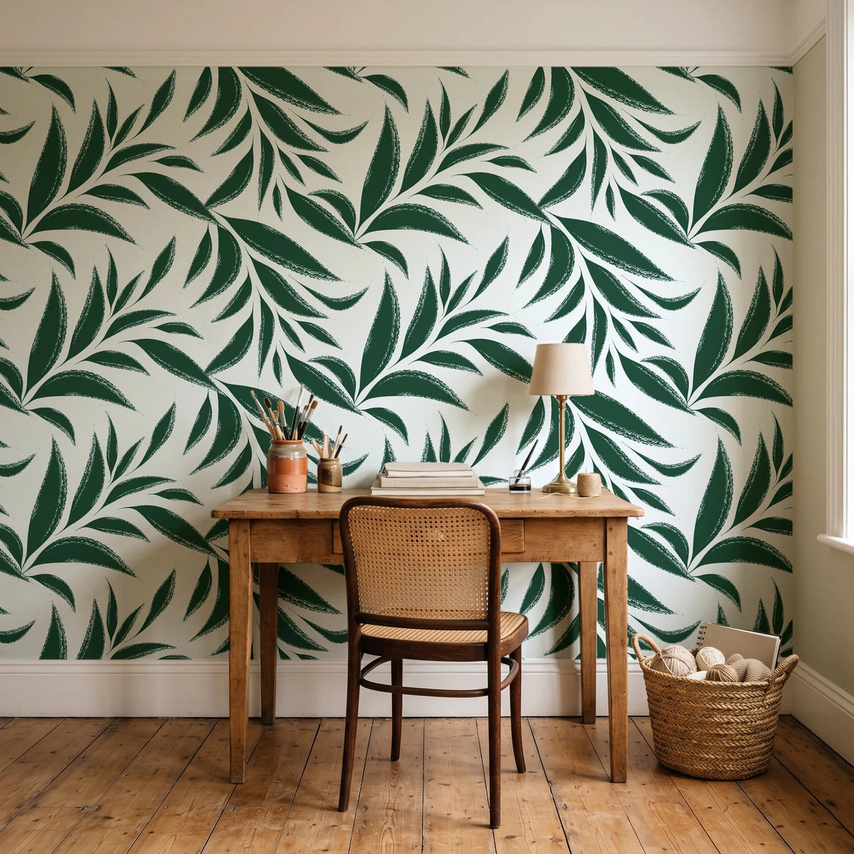 Ink Thicket Forest bold leaf wallpaper behind a vintage writing desk in a cozy craft-room home office