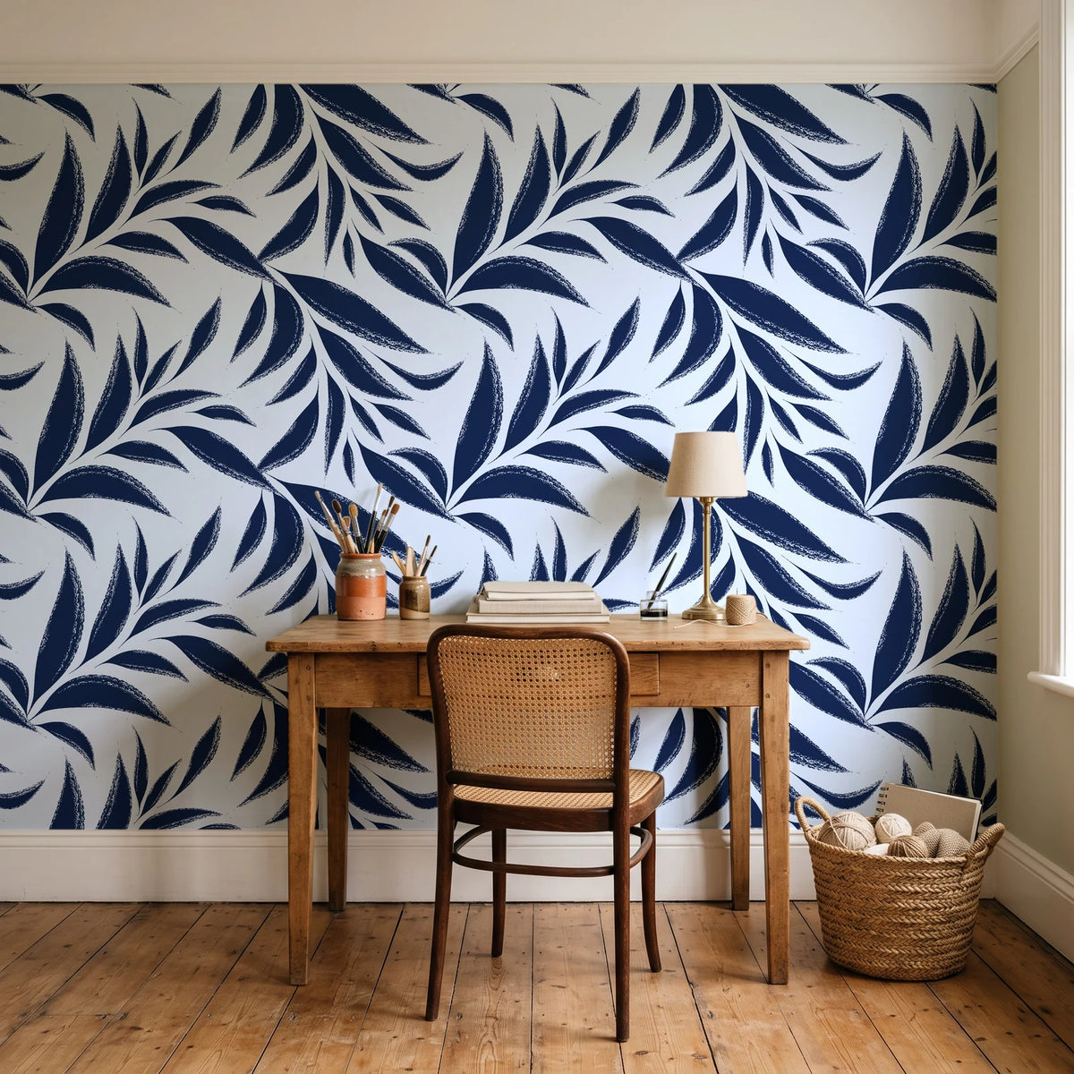 Ink Thicket Midnight bold leaf wallpaper behind a vintage writing desk in a cozy craft-room home office