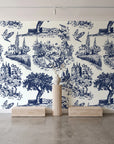 Inked Grove Midnight pastoral toile wallpaper behind a travertine pedestal and vase in a minimal boutique