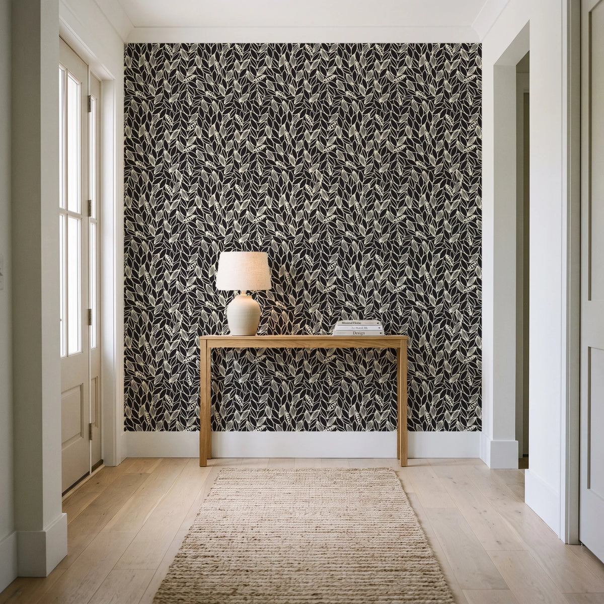Khaki Leaf Charcoal botanical leaf wallpaper behind a console table in a light entry hallway