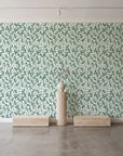 Khaki Leaf Evergreen botanical leaf wallpaper behind a travertine pedestal and vase in a minimal boutique