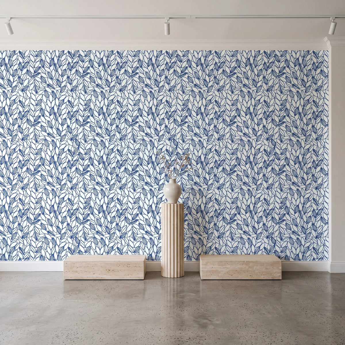 Khaki Leaf Indigo botanical leaf wallpaper behind a travertine pedestal and vase in a minimal boutique