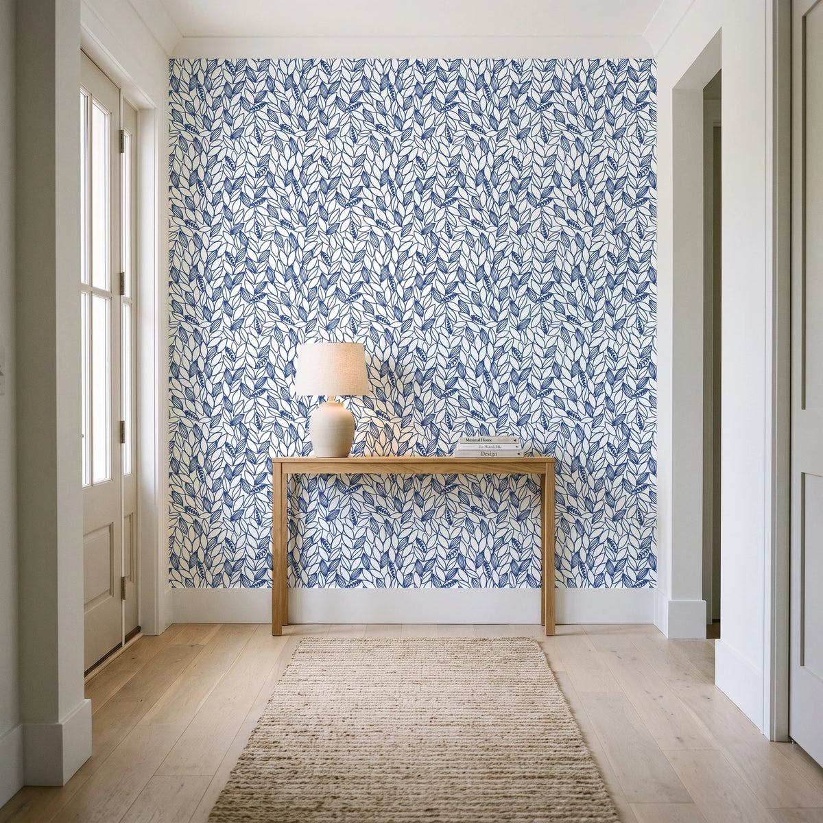 Khaki Leaf Indigo botanical leaf wallpaper behind a console table in a light entry hallway