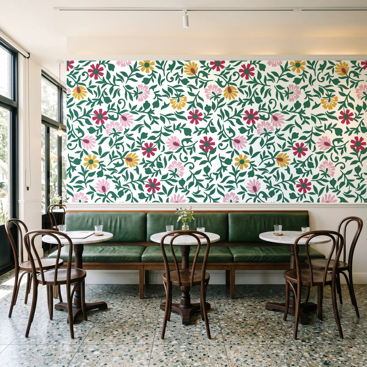 Matisse Reverie Emerald folk floral wallpaper above a green leather banquette in a sunlit neighborhood cafe