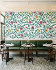 Matisse Reverie Emerald folk floral wallpaper above a green leather banquette in a sunlit neighborhood cafe