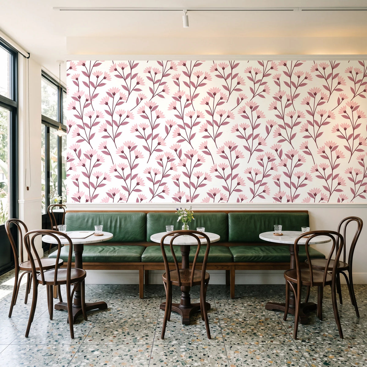 Meadow Light Blush meadow flower wallpaper above a green leather banquette in a sunlit neighborhood cafe