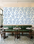 Meadow Light Cornflower meadow flower wallpaper above a green leather banquette in a sunlit neighborhood cafe