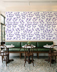 Meadow Light Lavender meadow flower wallpaper above a green leather banquette in a sunlit neighborhood cafe