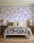 Meadow Wander Plum floral vine wallpaper behind a white cottage bed with a patchwork quilt in a cozy cottagecore bedroom