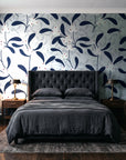 Mistletoe Trail Navy mistletoe wallpaper behind a tufted headboard in a dark, moody bedroom