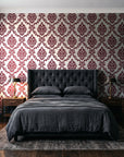 Misty Fern Romance Oxblood damask wallpaper behind a tufted headboard in a dark, moody bedroom