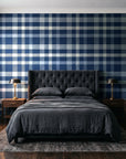 Moors & Mist Navy plaid wallpaper behind a tufted headboard in a dark, moody bedroom