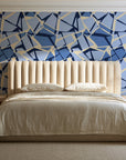 Muted Block Indigo geometric wallpaper behind a channel-tufted bed in a calm primary bedroom