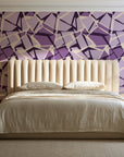 Muted Block Plum geometric wallpaper behind a channel-tufted bed in a calm primary bedroom