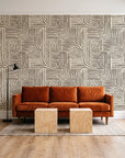 Nomad Stripe Espresso geometric wallpaper behind a rust velvet sofa in a bright coworking lounge