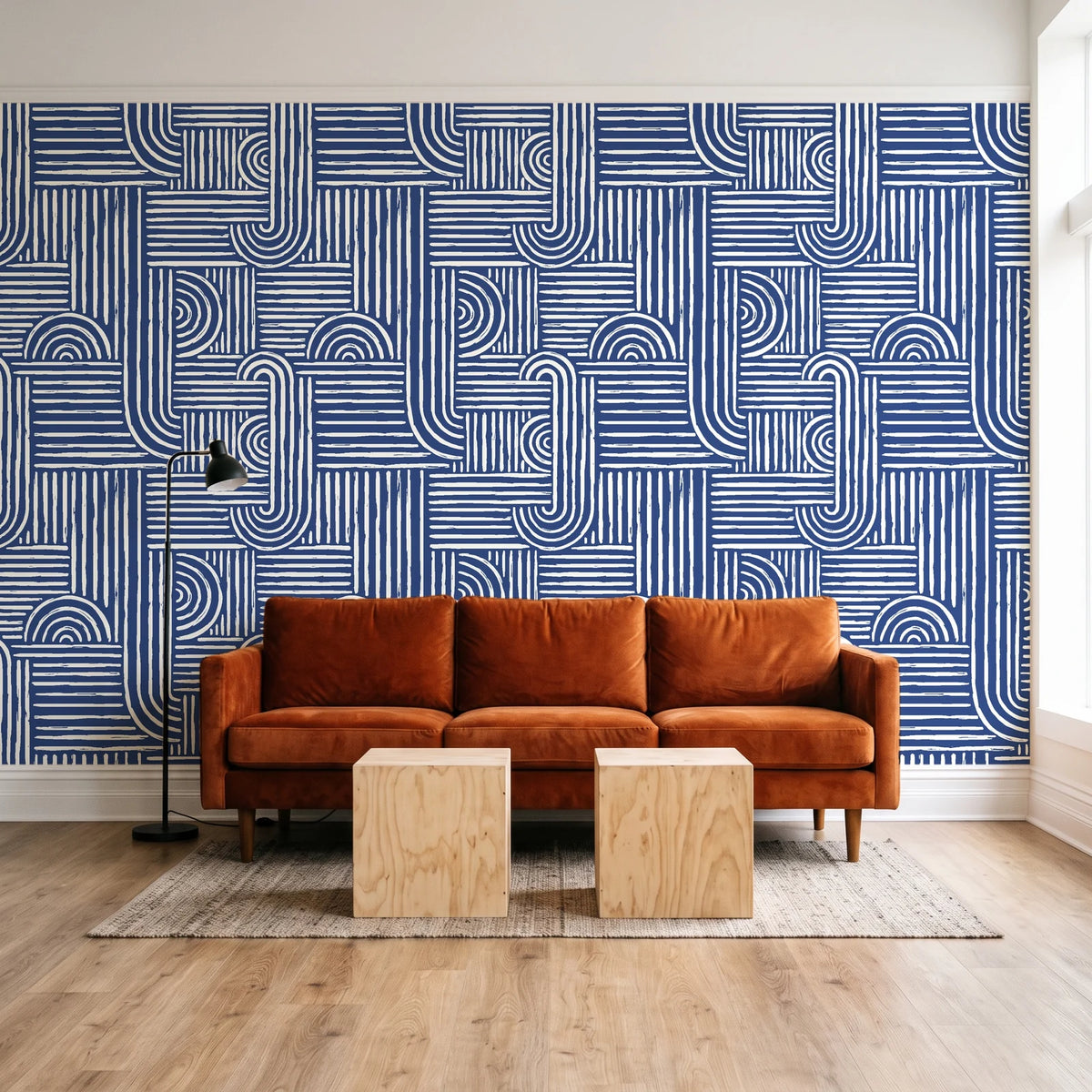 Nomad Stripe Indigo geometric wallpaper behind a rust velvet sofa in a bright coworking lounge