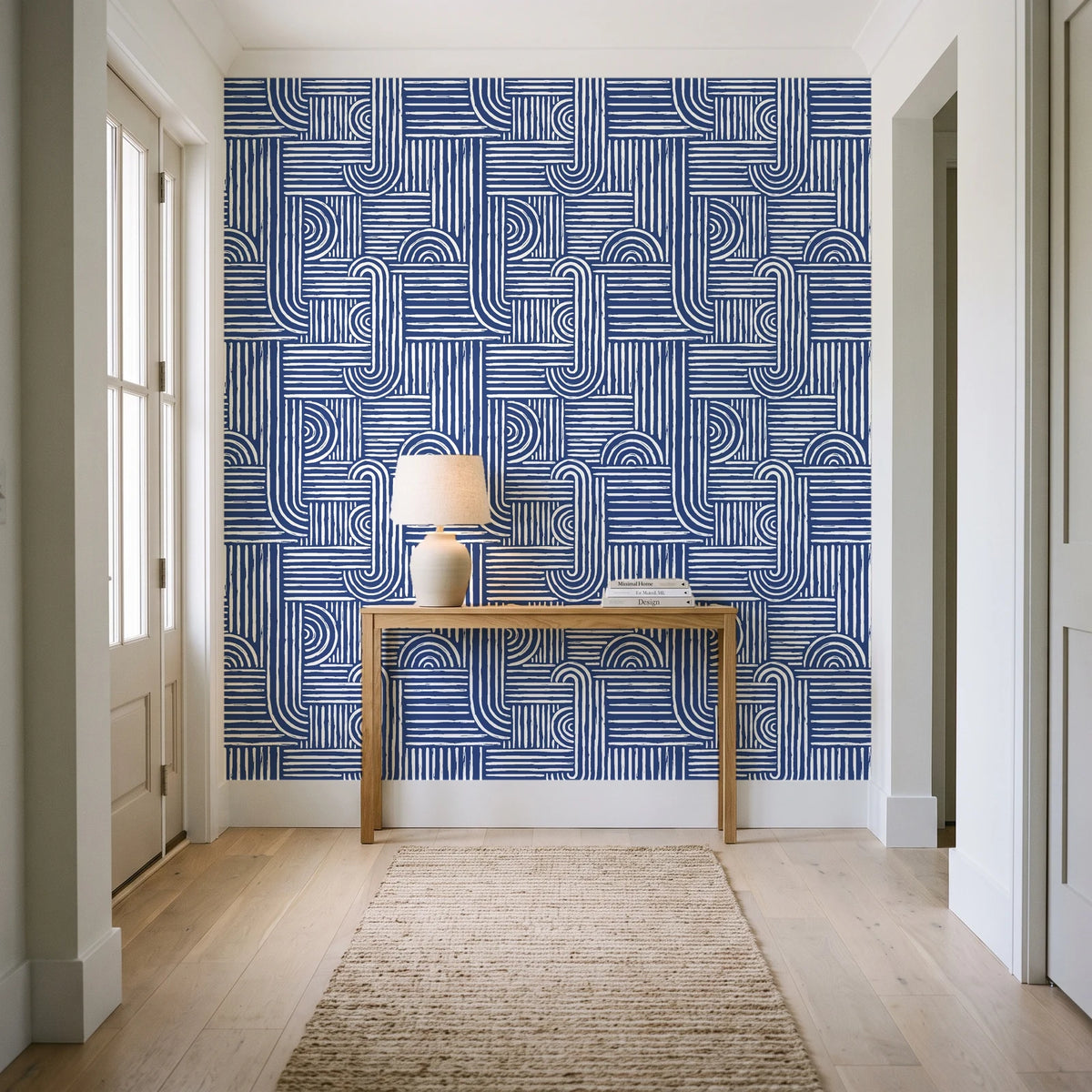 Nomad Stripe Indigo geometric wallpaper behind a console table in a light entry hallway