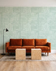 Nomad Stripe Sage geometric wallpaper behind a rust velvet sofa in a bright coworking lounge