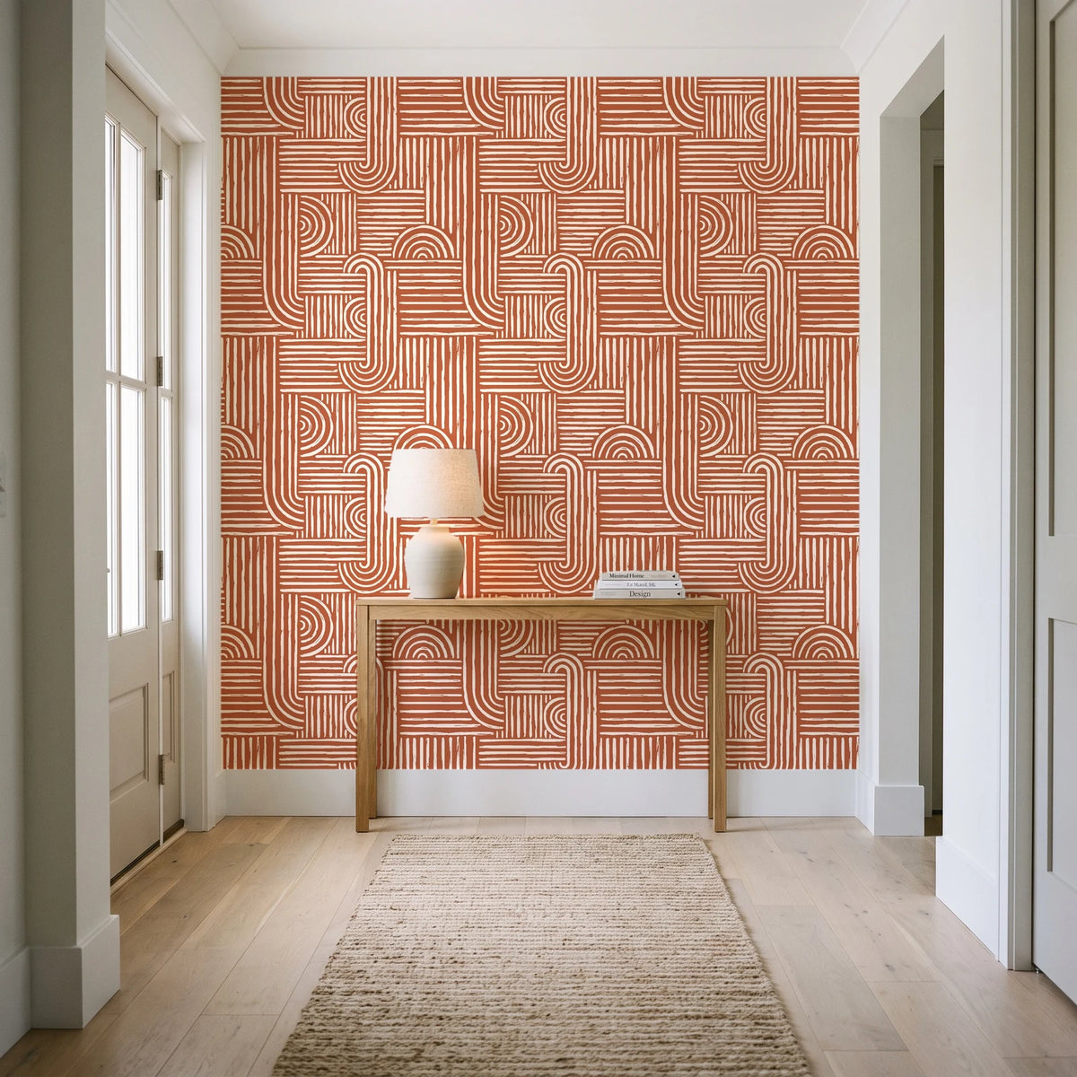Nomad Stripe Terracotta geometric wallpaper behind a console table in a light entry hallway