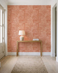 Nomad Stripe Terracotta geometric wallpaper behind a console table in a light entry hallway