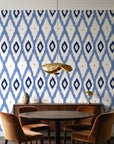 Ogee Loom Indigo ikat ogee wallpaper behind a walnut credenza and round table in an elegant dining room