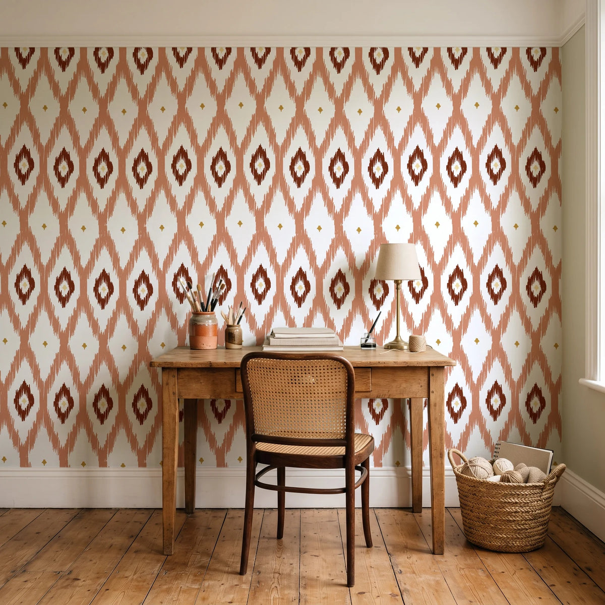 Ogee Loom Terracotta ikat ogee wallpaper behind a vintage writing desk in a cozy craft-room home office