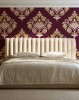 Old World Flora Burgundy floral damask wallpaper behind a channel-tufted bed in a calm primary bedroom