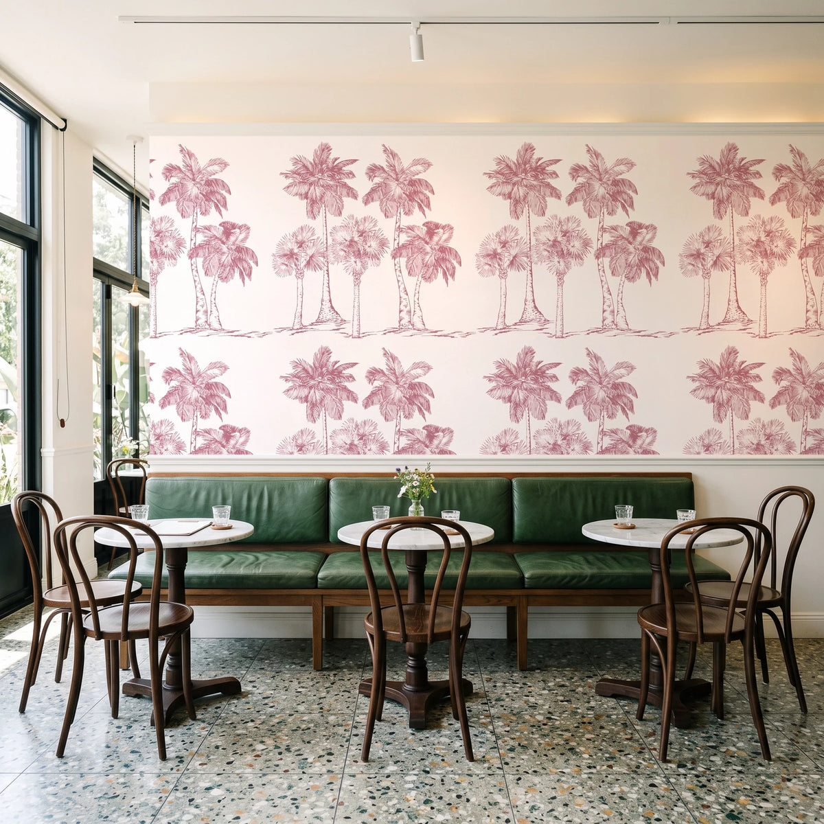 Palm Shade Rose palm grove wallpaper above a green leather banquette in a sunlit neighborhood cafe