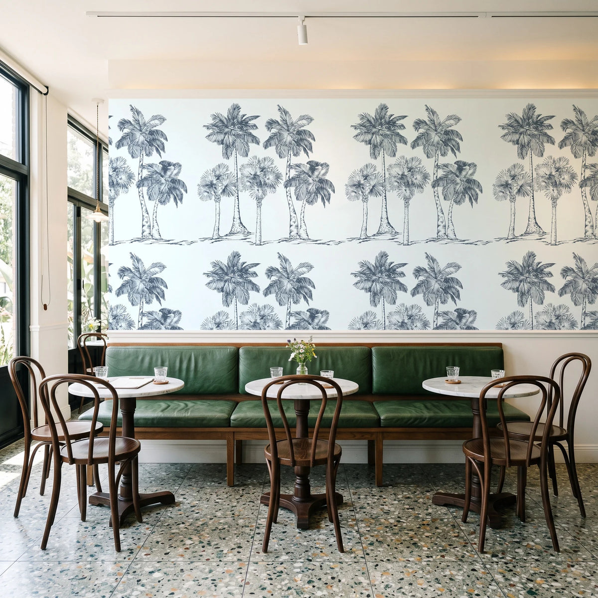 Palm Shade Slate palm grove wallpaper above a green leather banquette in a sunlit neighborhood cafe