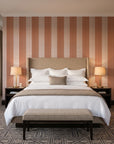 Parlor Stripe Terracotta geometric stripe wallpaper behind the headboard of a king bed in a contemporary hotel guest room