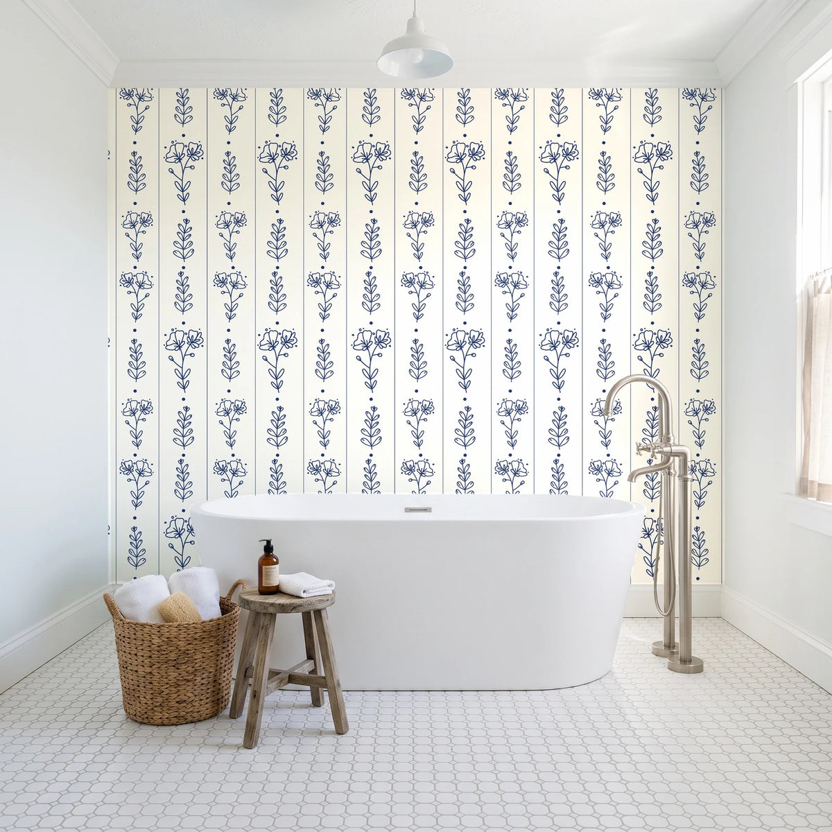 Petal & Thread Indigo botanical stem wallpaper behind a freestanding tub in a bright coastal bathroom