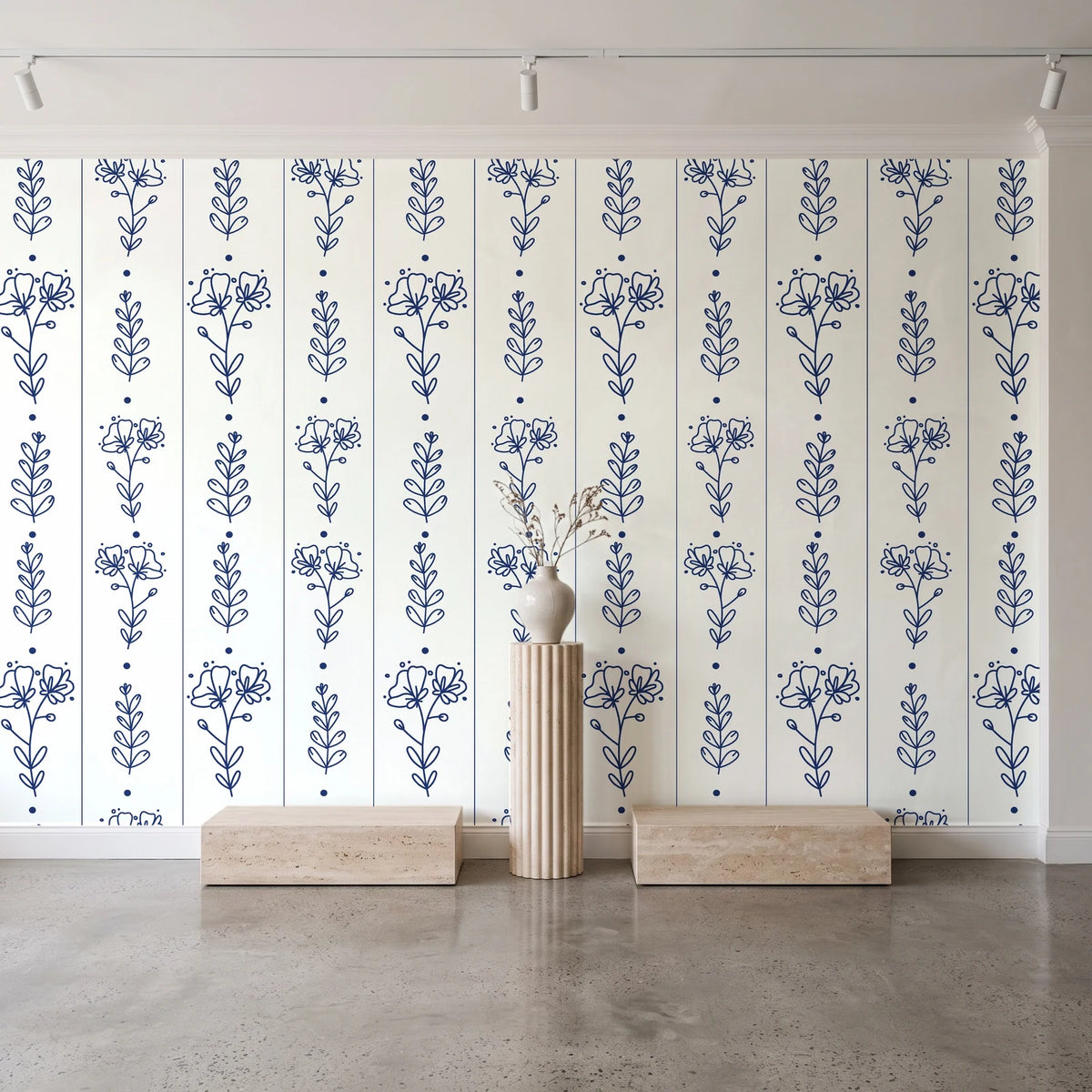 Petal & Thread Indigo botanical stem wallpaper behind a travertine pedestal and vase in a minimal boutique