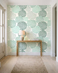 Petal Cascade Emerald spiral rosette wallpaper behind a console table in a light entry hallway