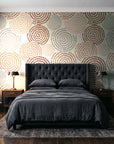 Petal Cascade Terracotta spiral rosette wallpaper behind a tufted headboard in a dark, moody bedroom
