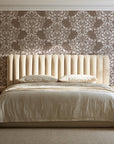 Petal Symphony Mocha baroque damask wallpaper behind a channel-tufted bed in a calm primary bedroom