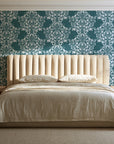 Petal Symphony Teal baroque damask wallpaper behind a channel-tufted bed in a calm primary bedroom