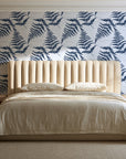 Pewter Fern Navy fern wallpaper behind a channel-tufted bed in a calm primary bedroom