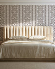 Porcelain Filigree Taupe filigree damask wallpaper behind a channel-tufted bed in a calm primary bedroom