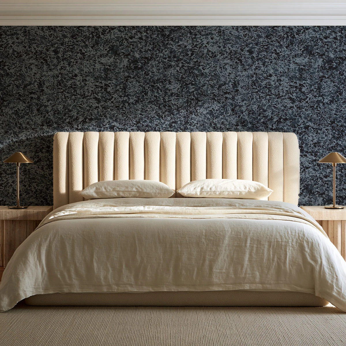 Quiet Camo Charcoal abstract wallpaper behind a channel-tufted bed in a calm primary bedroom